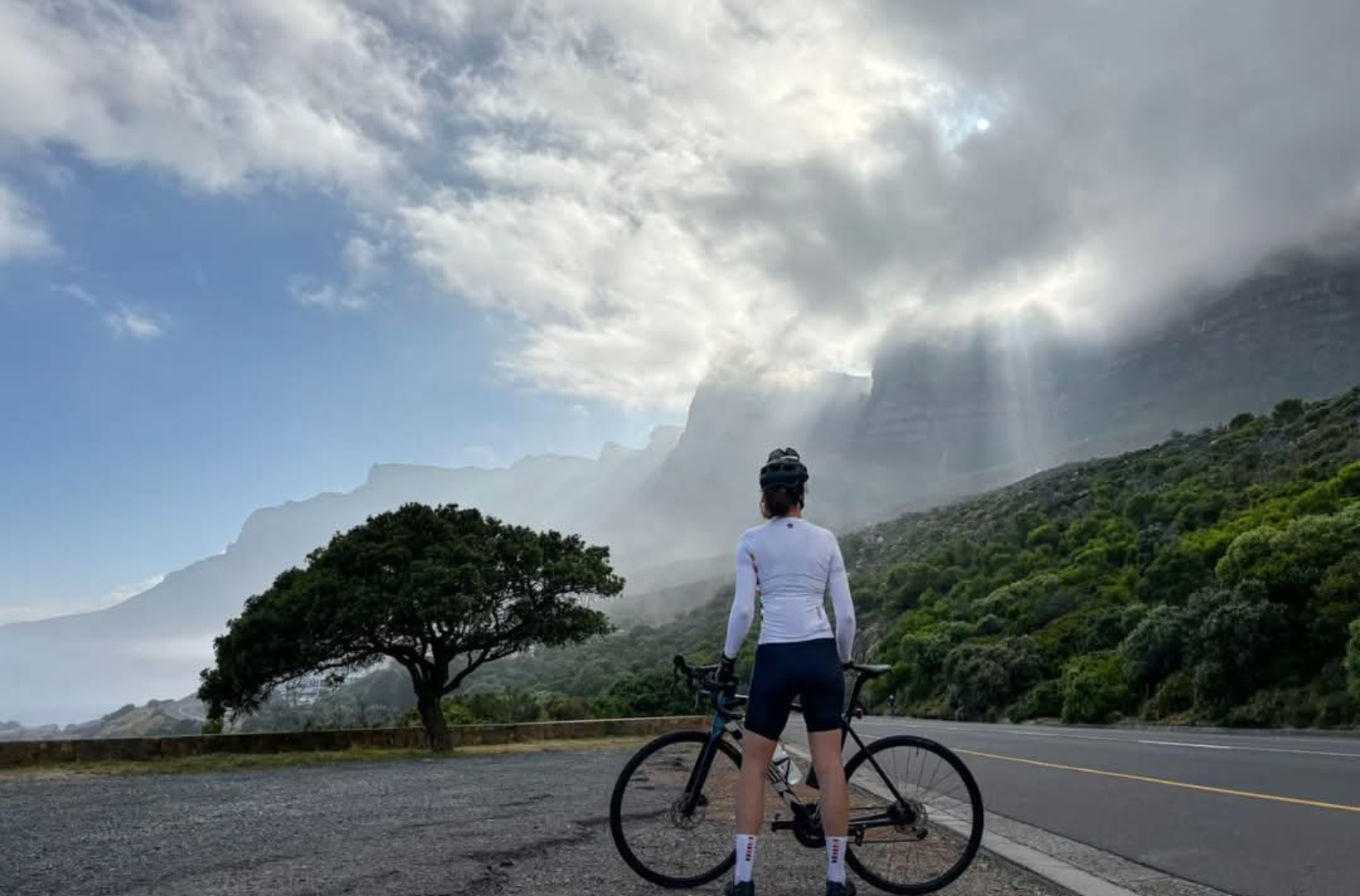 a wellness woman standing on a road with a bicycle